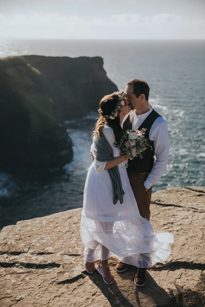 Brautpaar küsst sich an windigen Klippen in Europa bei einem Elopement