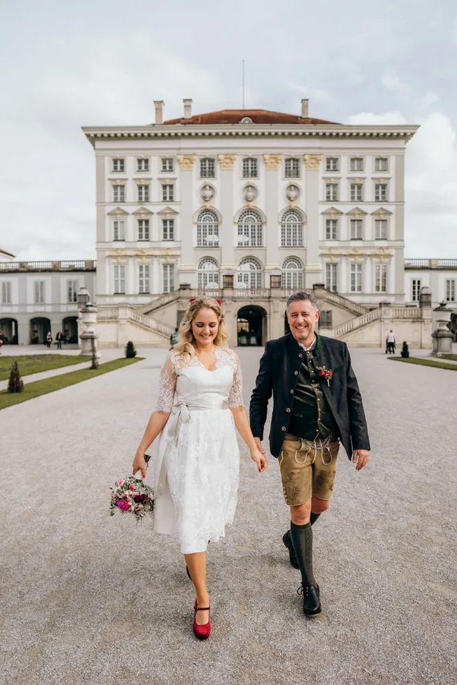Glückliches Paar in traditioneller bayerischer Tracht nach standesamtlicher Trauung in Schloss Ismaning, fotografiert von MOKATI