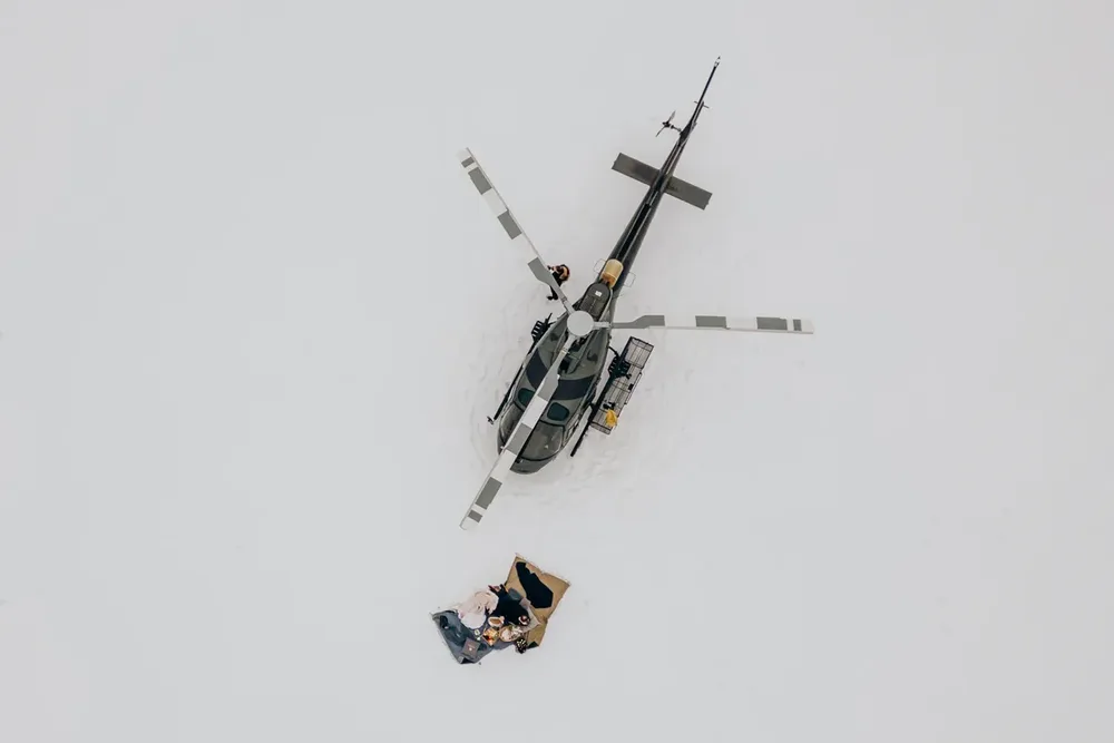 Schwarzer Hubschrauber auf schneebedecktem Gipfel – Hochzeitsreportage MOKATI