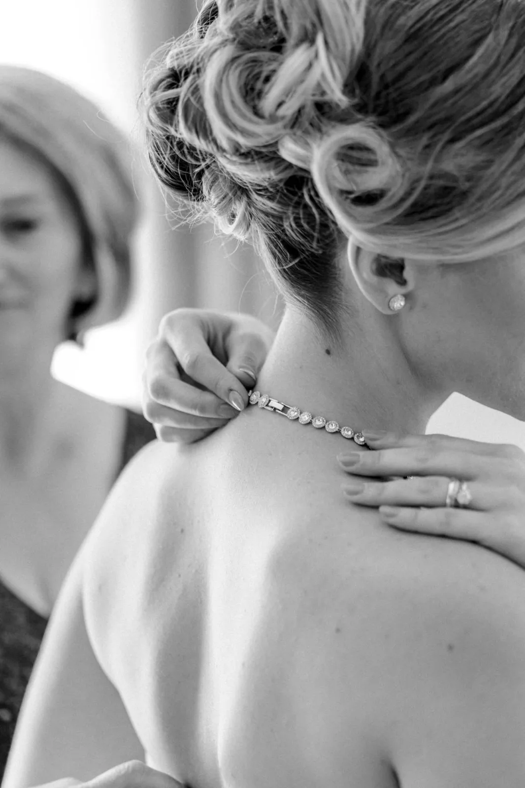 Beim Getting Ready wird der Braut die Kette geschlossen, Schwarzweißaufnahme