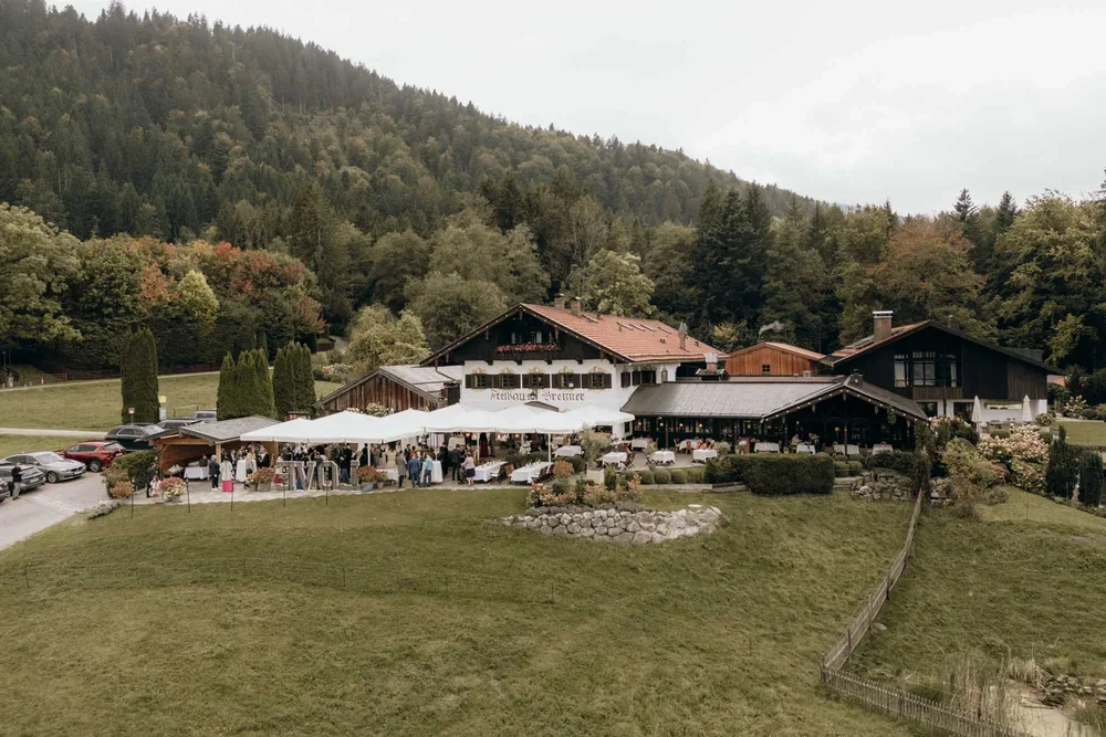 Freihaus Brenner am Tegernsee in Bad Wiessee mit Hochzeitsgesellschaft, Festzelt und bewaldetem Berg im Hintergrund